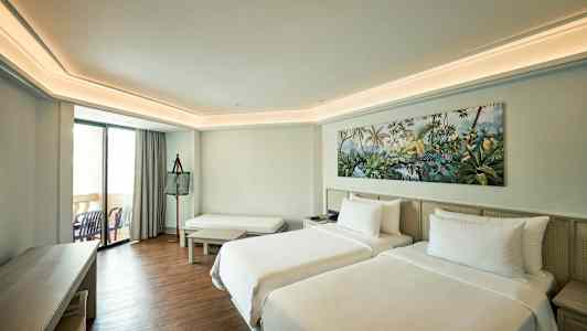 Hotellrum med två enkelsängar, sittplats och balkong. (AI-genererad text)