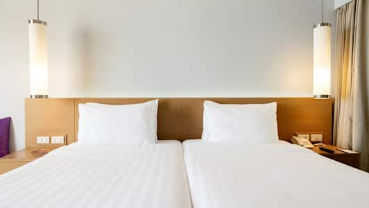 Två enkelsängar med vita lakan och kuddar. (AI-genererad text)