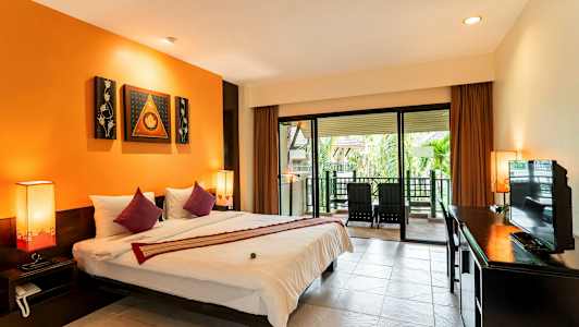 Ett hotellrum med en stor säng, orangea väggar och en terrass med stolar utanför. (AI-genererad text)