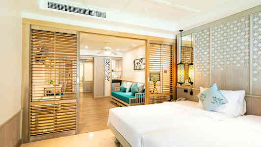 Hotelrum med en dubbelsäng, blå soffa och trädetaljer. (AI-genererad text)