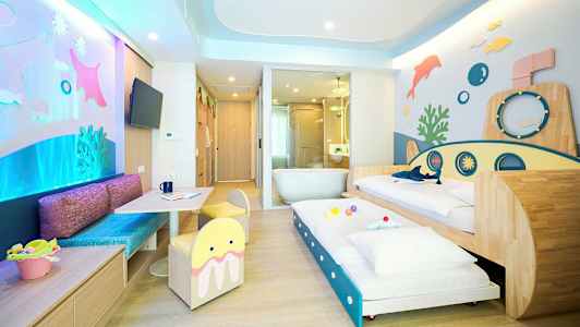 Ett färgglatt familjerum med undervattenstema, inkluderande sängar och lekutrymme. (AI-genererad text)