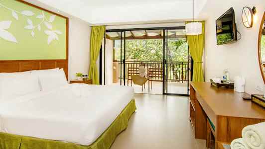 Ett hotellrum med en dubbelsäng, skrivbord och utsikt mot en balkong. (AI-genererad text)