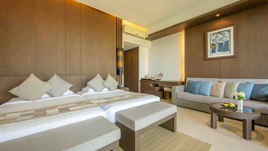 Ett hotellrum med två sängar, en soffa och ett bord. (AI-genererad text)