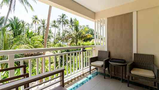 Bild av en balkong med två sittplatser och bord, där utsikten består av tropiska palmer. (AI-genererad text)