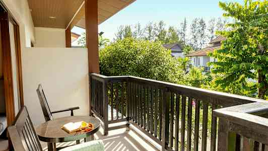 Utsikt från en balkong med bord, stolar och träd omkring. (AI-genererad text)