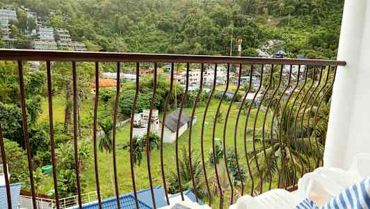 En balkong med utsikt över en grön dal och byggnader. (AI-genererad text)