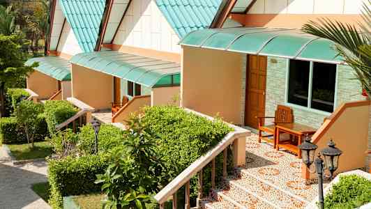 Rad av små hus med gröna tak och trappor omgivna av växter. (AI-genererad text)