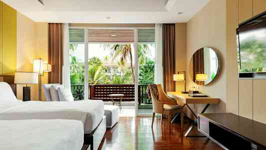 Modernt hotellrum med två enkelsängar, skrivbord, spegel och balkong med grön utsikt. (AI-genererad text)