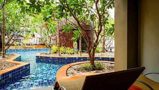 En pool omgiven av träd och sittplatser. (AI-genererad text)