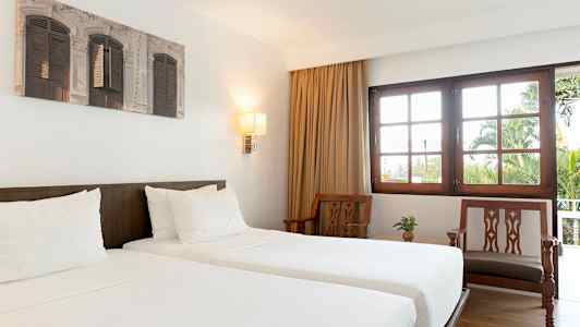 Hotellrum med två enkelsängar och möbler i ljust trä. (AI-genererad text)