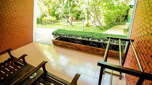 Terrass med två mörka trästolar och utsikt mot en trädgård. (AI-genererad text)