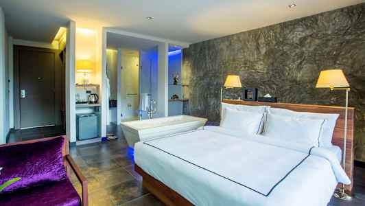 Ett modernt hotellrum med en dubbelsäng, en badkar bredvid, och en stilren inredning. (AI-genererad text)