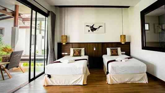 Dubbelrum med två enkelsängar, fönster och dekorerade kuddar. (AI-genererad text)