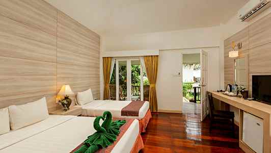 Ett hotellrum med två sängar, en dörr som leder ut till en trädgård, ett skrivbord med en stol samt lampor och dekorationer. (AI-genererad text)