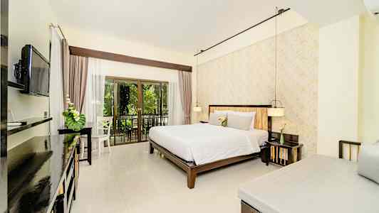 Ett rum med en dubbelsäng, en säng i hörnet och en TV på väggen, med en balkong som vetter mot grönska. (AI-genererad text)