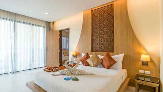 Bild som visar ett modernt hotellrum med en uppsatt dubbelsäng, prydd med dekorativa kuddar och handdukar vikta som svanar. (AI-genererad text)