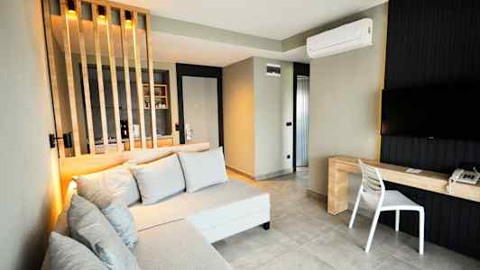 Ett modernt hotellrum med en soffa, tv och skrivbord, samt en skillnadsvägg för köksdelen. (AI-genererad text)