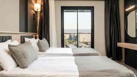 Rum med två enkelsängar, modernt inrett med neutral färgpalett. (AI-genererad text)