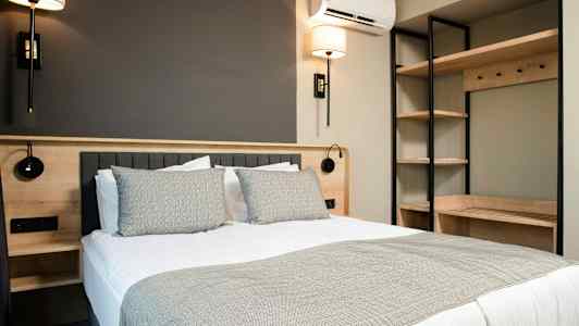 Ett modernt sovrum med en dubbelsäng, sänglampor och hyllförvaring. (AI-genererad text)