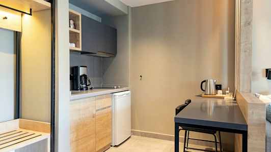 Ett kök med träskåp, kaffekokare, kylskåp och ett bord med vattenkokare. (AI-genererad text)