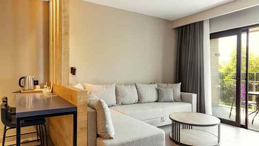 Modernt vardagsrum med grå soffa, träbord och stora fönster. (AI-genererad text)