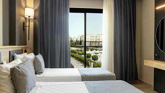 Hotellrum med två enkelsängar och fönster med utsikt mot ett poolområde. (AI-genererad text)