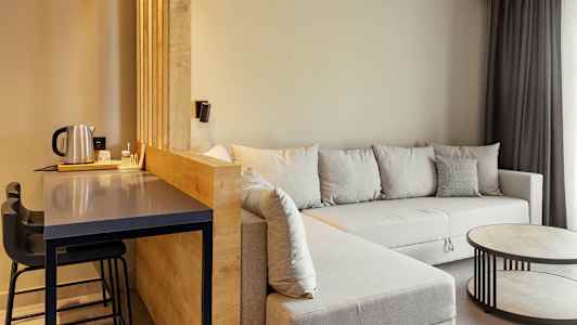 Rum med sittgrupp, grå soffa, och ett bord samt en bardisk med stolar. (AI-genererad text)