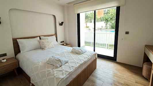 Ett sovrum med en dubbelsäng, ett fönster som vetter mot en uteplats och en pool. (AI-genererad text)