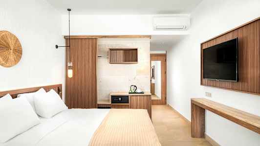 Ett stilfullt hotellrum med en säng, en TV och en liten kökshörna. (AI-genererad text)