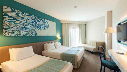 Hotellrum med två sängar, skrivbord, soffa och TV. (AI-genererad text)