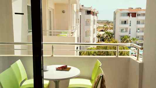 Bild av en balkong med bord och stolar samt utsikt över omgivande byggnader. (AI-genererad text)