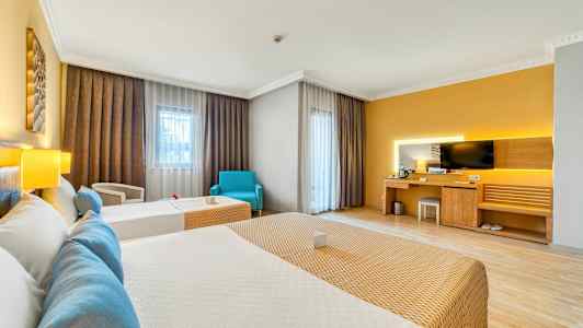 Ett hotellrum med två bäddar, en skrivbordshörna med TV och stora fönster med gardiner. (AI-genererad text)