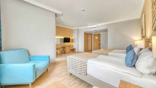 Ett hotellrum med två enkelsängar, en blå stol och en TV på en byrå. (AI-genererad text)