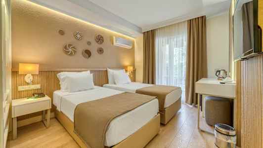 Ett hotellrum med två enkelsängar, en skrivbordshörna och neutrala färgtoner. (AI-genererad text)