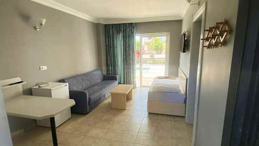 Ett hotellrum med soffa, bord och säng, samt utsikt mot en balkong. (AI-genererad text)