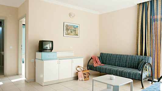 Hotellrum med soffa, bord, garderob och liten TV. (AI-genererad text)