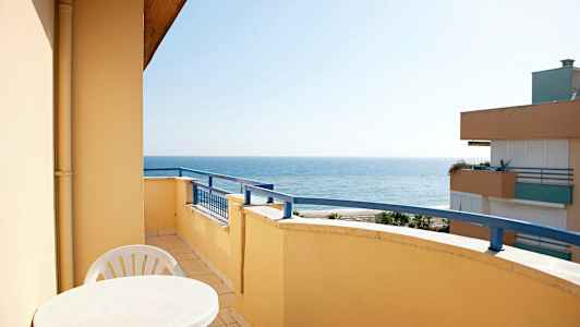 En balkong med bord och stolar, med havsutsikt. (AI-genererad text)