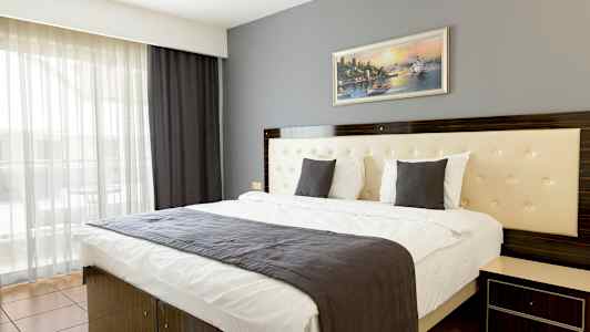 Ett modernt hotellrum med en dubbelsäng, en grå sänglampa och en tavla på väggen. (AI-genererad text)