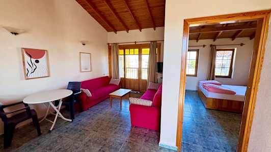 Vardagsrum med röda soffor och trämöbler samt ett anslutande sovrum. (AI-genererad text)