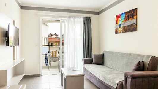 En ljus vardagsrum med soffa, bord och öppen balkong. (AI-genererad text)