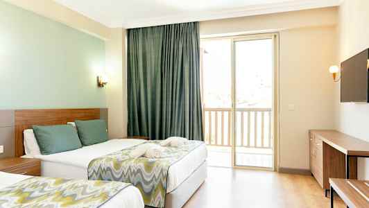 Ett hotellrum med två sängar, en TV på väggen och ett fönster med balkong. (AI-genererad text)