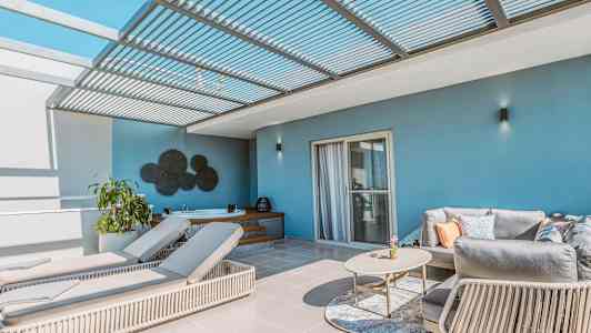 En terrass med solstolar, soffa och bord under ett pergolatak. (AI-genererad text)