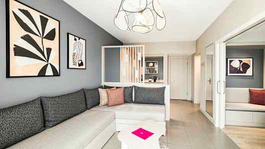 Ett modernt vardagsrum med grå väggar, en hörnsoffa och konst på väggen. (AI-genererad text)