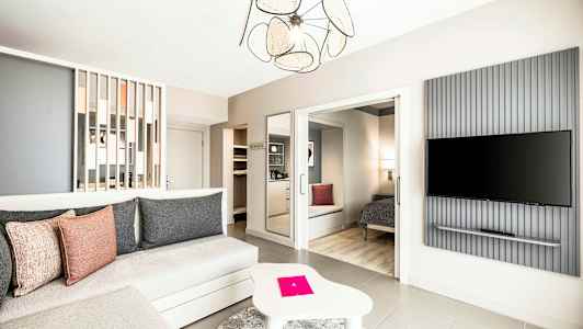 Ett rymligt och modernt inrett hotellrum med sittgrupp, sovplats och en väggmonterad TV. (AI-genererad text)