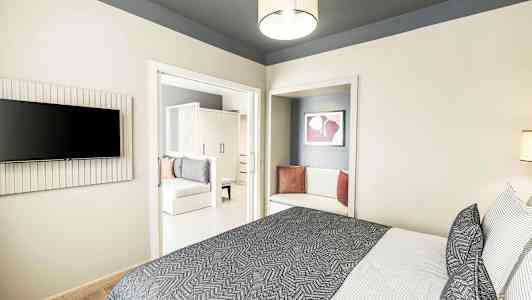 Modernt hotellrum med säng, textilier och sittdel. (AI-genererad text)