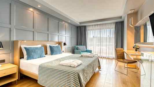 Hotellrum med en dubbelsäng, två fåtöljer och ett skrivbord. (AI-genererad text)