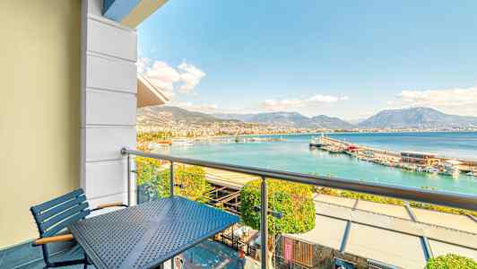 Balkong med utsikt över en hamn och berg i fjärran. (AI-genererad text)