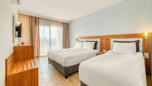 Modernt hotellrum med två sängar, ljusa färger och stora fönster. (AI-genererad text)