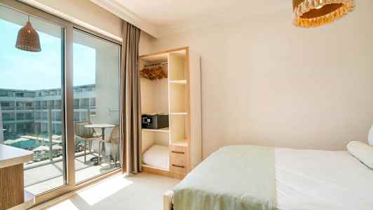 Hotellrum med säng, garderob och balkong som vetter mot en pool. (AI-genererad text)