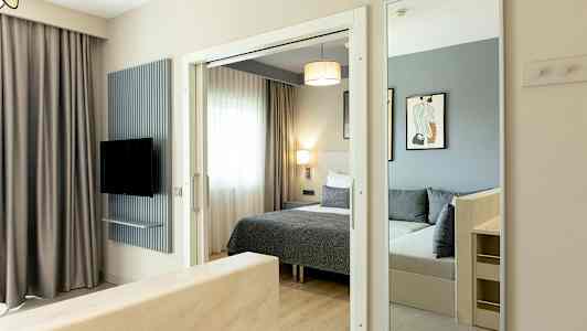 Bild av ett hotellrum med säng, spegel och TV. (AI-genererad text)